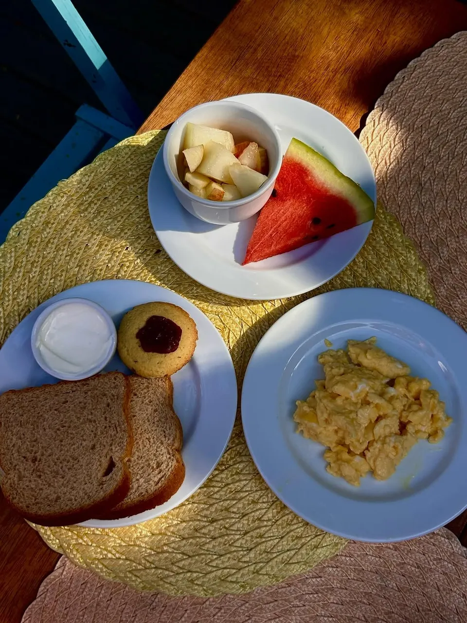 Café da manhã servido com frutas, pão e ovos mexidos