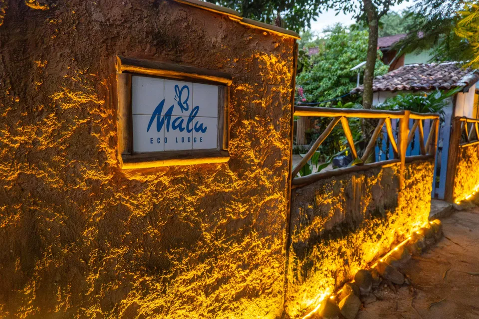 Placa da Malu Eco Lodge no muro iluminado