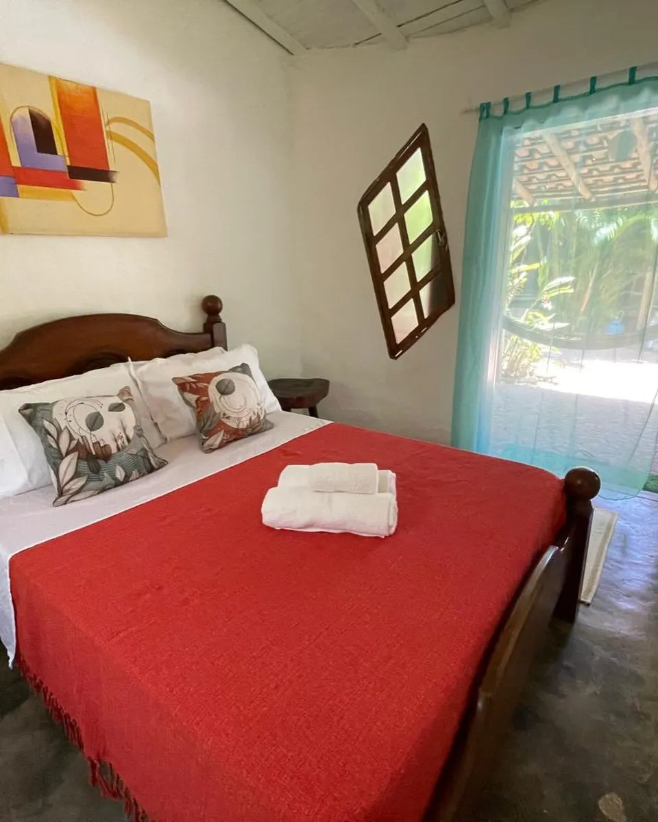 Suíte Carapau com colcha vermelha e quadro colorido