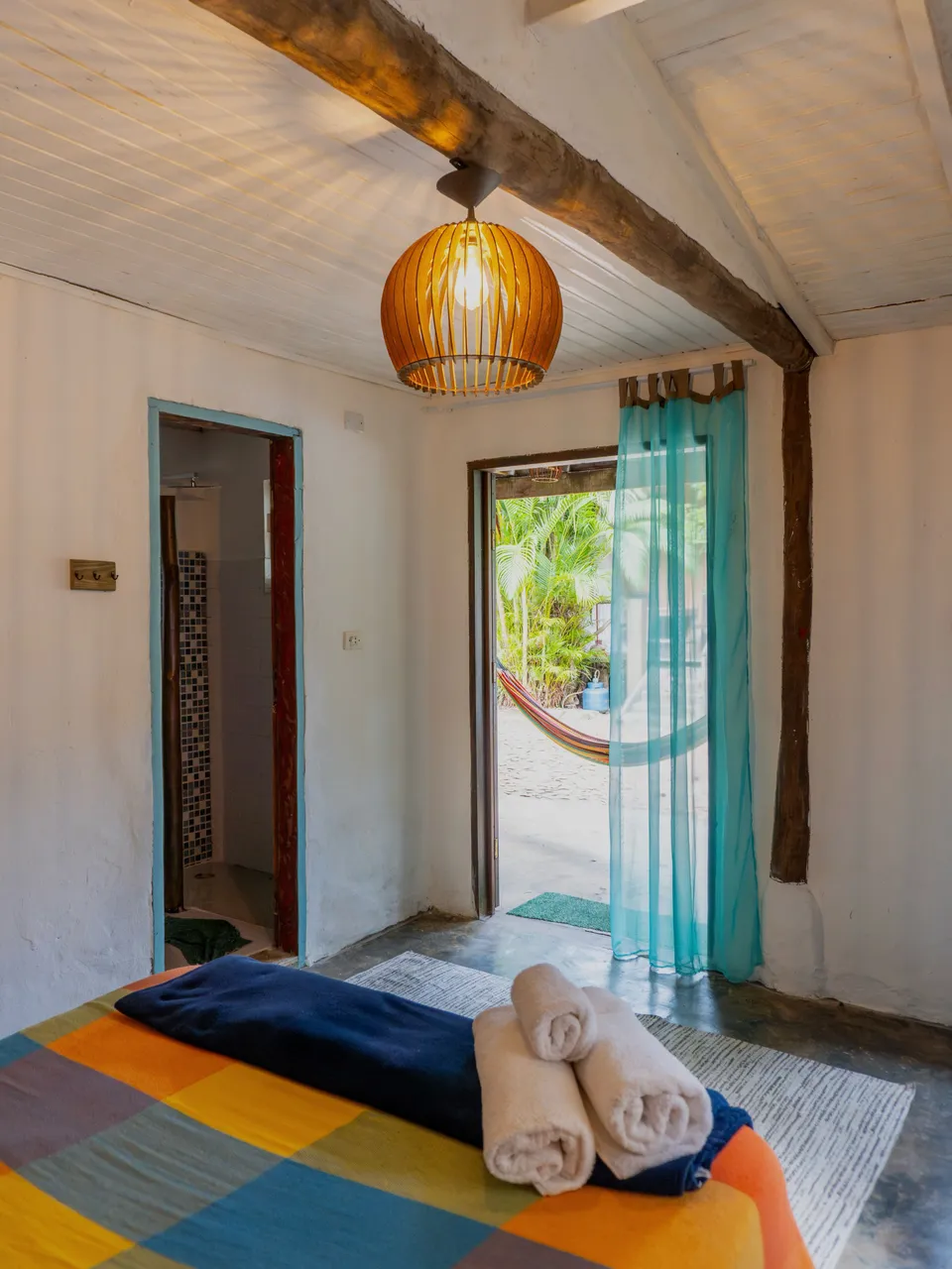 Suíte Espada com toalhas sobre a cama e porta para a varanda